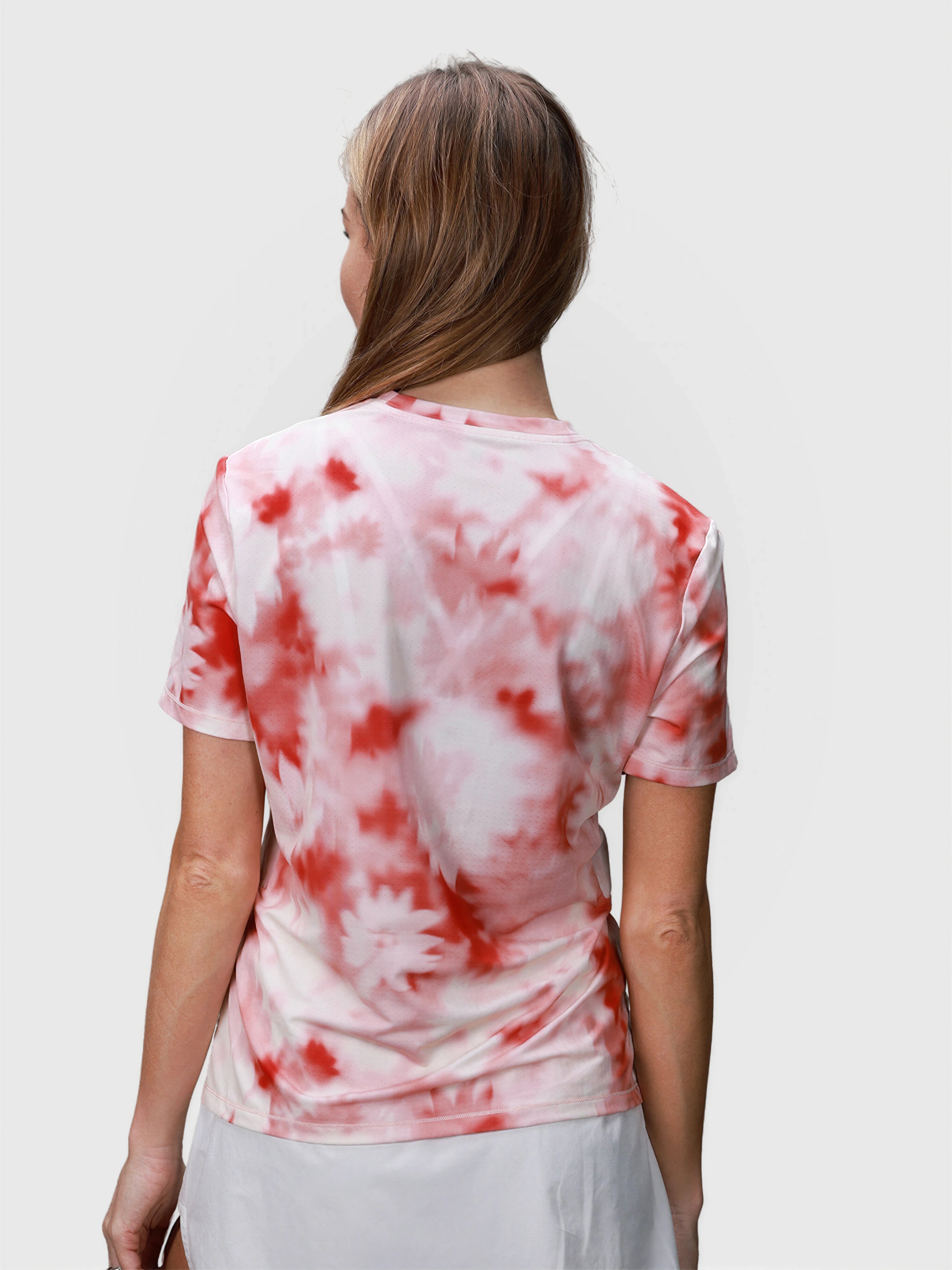 Back view of woman wearing pink petal tie-dye PowerMove Performance Tee in padel apparel by MUEV
