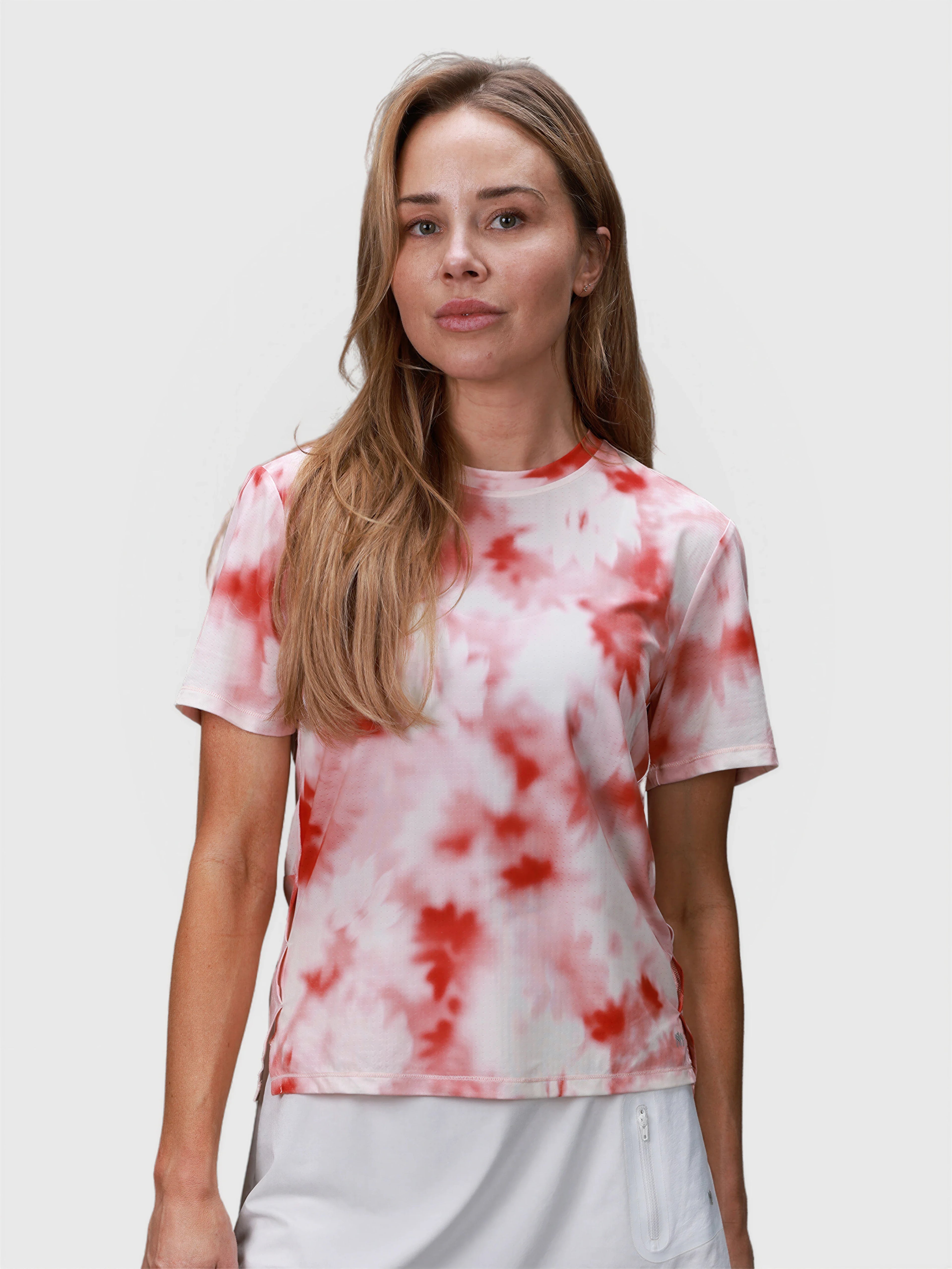 Front view of woman wearing pink petal PowerMove Performance Tee in padel clothing by MUEV