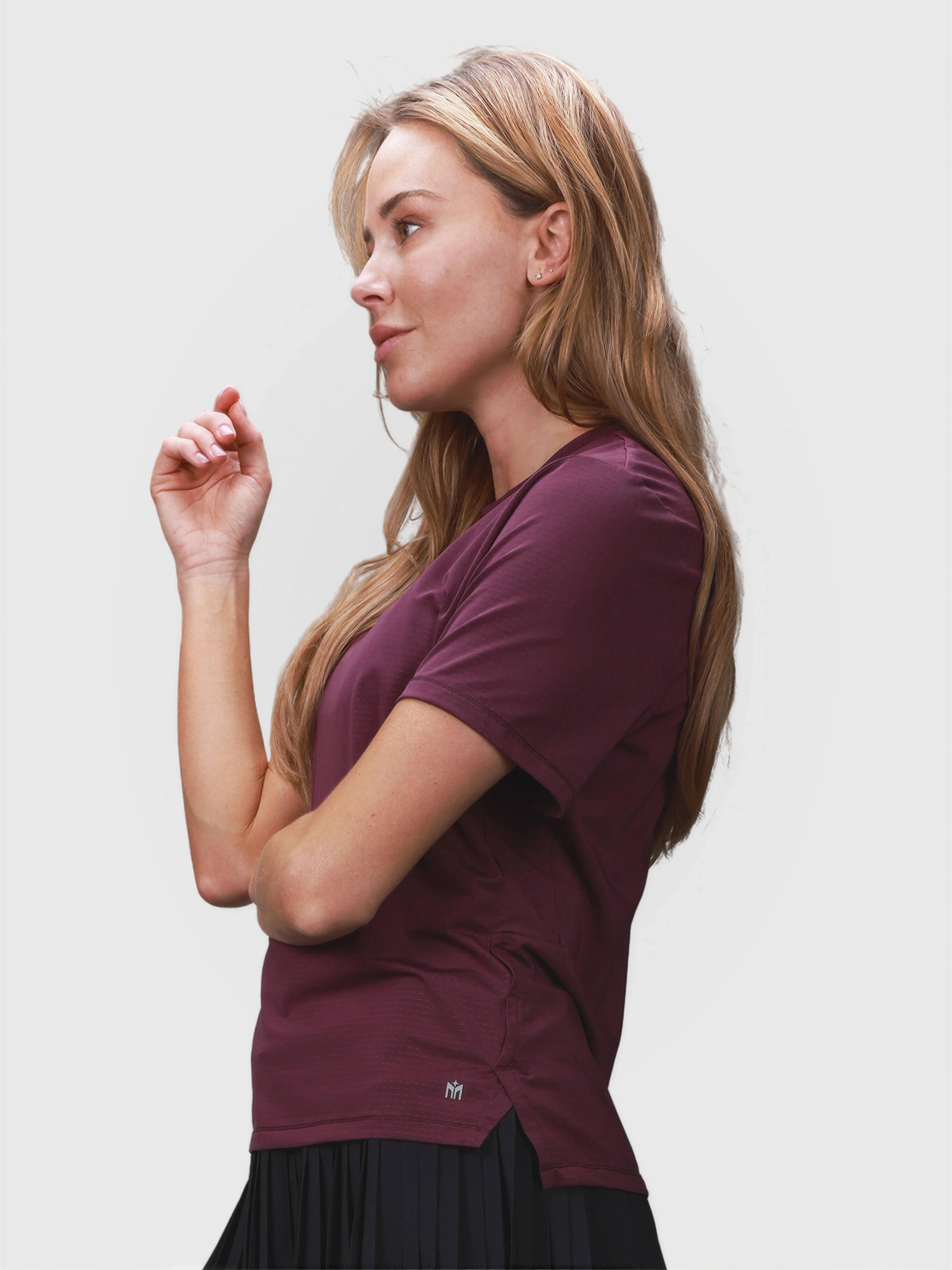 Side profile of woman wearing plum PowerMove Performance Tee in padel apparel by MUEV
